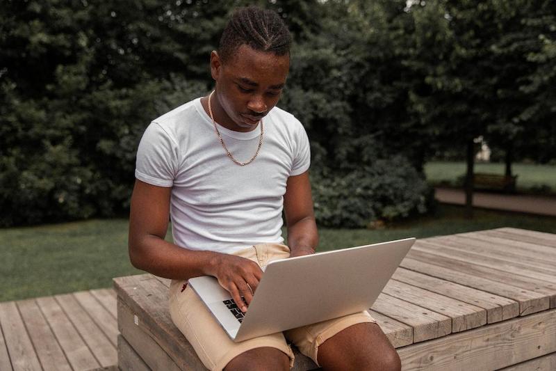 A person sitting on a bench using a computer